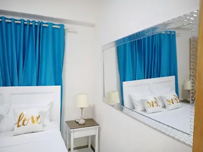 a bedroom with two beds with blue curtains and a mirror at Elegant and confortable close to Boca Chica Beach in Boca Chica