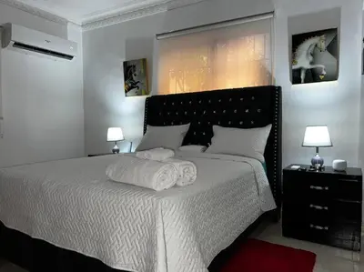 a bedroom with a large white bed with two lamps at Entire apartment Tu Nido De Amor 2 Santo Domingo West in Santo Domingo