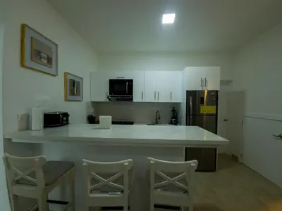 a kitchen with a large white counter top and chairs at 2JA Management Group - Condos White Hill in Sosúa