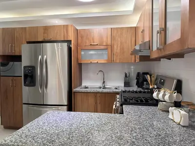 a kitchen with wooden cabinets and a stainless steel refrigerator at Rustic Elegance St in Santiago de los Caballeros