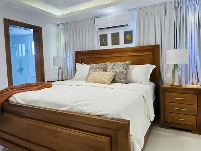 a bedroom with a large bed with white sheets and pillows at Rustic Elegance St in Santiago de los Caballeros