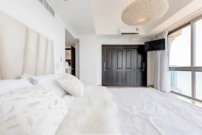 a bedroom with a large white bed and a television at Habitación Privada con vista al mar Ámbar, Malecon Santo Domingo in Santo Domingo