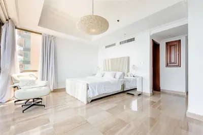 a white bedroom with a bed and a chair at Habitación Privada con vista al mar Ámbar, Malecon Santo Domingo in Santo Domingo