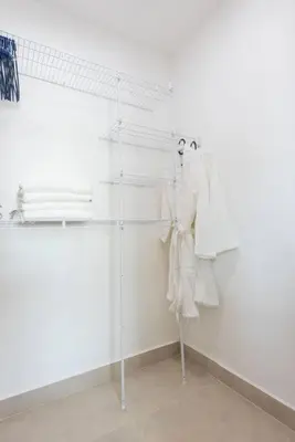 a room with white walls and white clothes on shelves at Stunning infinity pool apartment in Santo Domingo