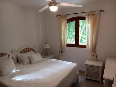 a bedroom with a white bed and a window at Bonita Village Beachfront Apt with Pool & Balcony in Las Terrenas
