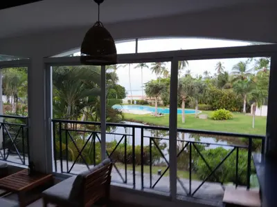 a view from the living room of the pool through the windows at Bonita Village Beachfront Apt with Pool & Balcony in Las Terrenas