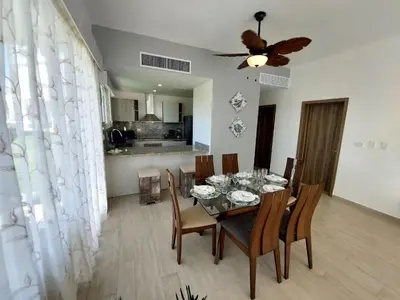a dining room with a table with chairs and a ceiling fan at Hard Rock Getaway • 2BR with Golf + Pool Views in Punta Cana