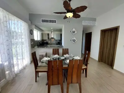 a dining room table with chairs and a ceiling fan at Hard Rock Getaway • 2BR with Golf + Pool Views in Punta Cana