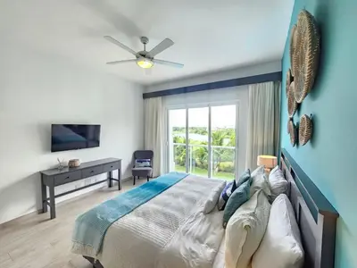 a blue bedroom with a bed and a window at 2BR Beach Condo • Prime Location Across Hard Rock in Punta Cana