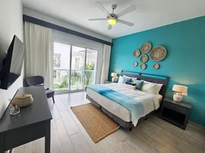 a bedroom with a blue wall with a bed and a desk at 2BR Beach Condo • Prime Location Across Hard Rock in Punta Cana
