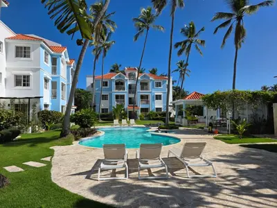 a villa with a swimming pool with chairs and palm trees at Madonna1 pool beach los corales Arenas de Bavaro in Punta Cana