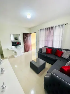 a living room with a black couch and red pillows at Oasis de Paz 4 in Jarabacoa
