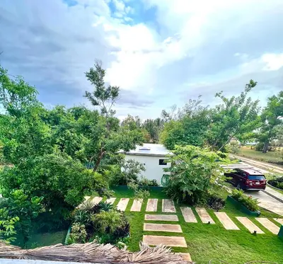 a yard with a white house and a car at CASAS LEON Casita de playa #2 in Santa Bárbara de Samaná
