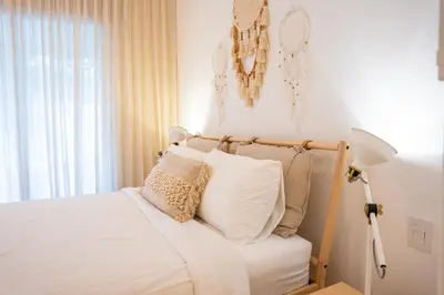 a bedroom with a bed with white sheets and pillows at Fortunity Beach Tower-2 BDR with pool view in San Felipe de Puerto Plata