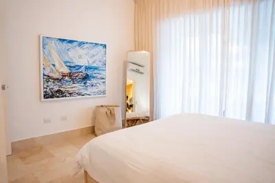 a bedroom with a bed and a painting on the wall at Fortunity Beach Tower-2 BDR with pool view in San Felipe de Puerto Plata