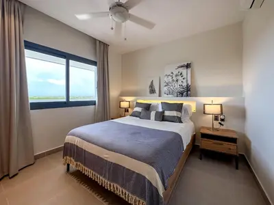 a bedroom with a bed and a large window at Fantastic Penthouse at Golf Course in Punta Cana