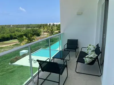 a balcony with three chairs and a swimming pool at Hard Rock at Cana Rock 3 by Unwind Properties in Punta Cana