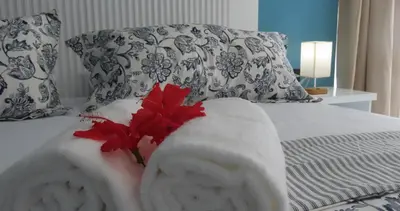 a bed with white towels and red flowers on it at All Seasons Hotel in Bayahibe