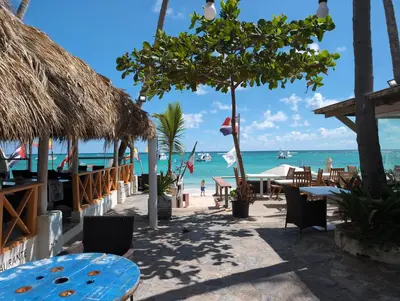 a beach with tables and chairs and the ocean at Dios es Fiel - Ali Hotel in Punta Cana