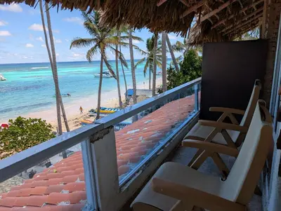 two chairs on a balcony overlooking the beach at Dios es Fiel - Ali Hotel in Punta Cana