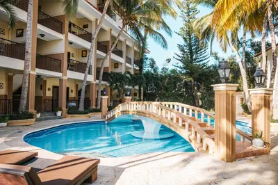 a bridge over a pool at a hotel with palm trees at Hotel Plaza Brisas in Punta Cana