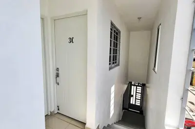 a white hallway with a door and a stair case at Apartamento acogedor Ashmi in Santiago de los Caballeros