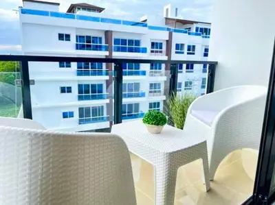 a balcony with white chairs and a table and a building at Torre Solarium next to PUCMM in Santiago de los Caballeros