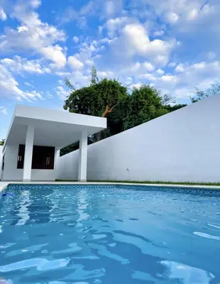 a house with a swimming pool and a white wall at Torre Solarium next to PUCMM in Santiago de los Caballeros