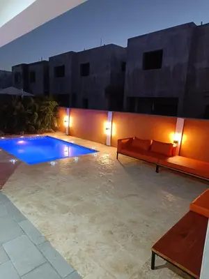 a patio with a couch and a pool at night at Villa Selina in Punta Cana