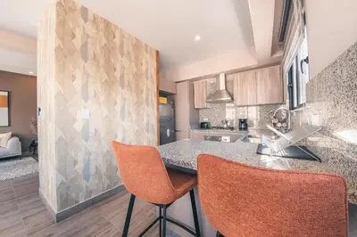 a kitchen with a counter and two orange chairs at Breakfast Included at Regatta Living 802 in Los Prados
