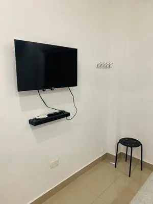 a flat screen tv on a white wall with a stool at Plataview Apartahotel apt 4C in Monte Plata