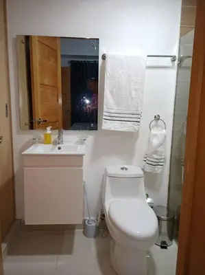 a bathroom with a toilet and a sink and a mirror at El mejor apartamento cerca de la playa de Boca Chica in Boca Chica