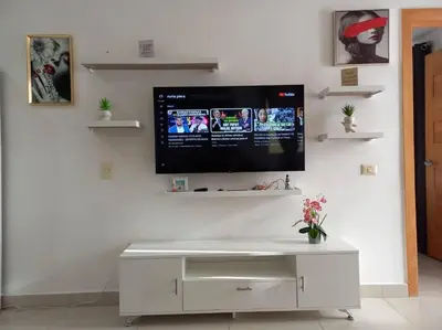 a flat screen tv hanging on a white wall at El mejor apartamento cerca de la playa de Boca Chica in Boca Chica