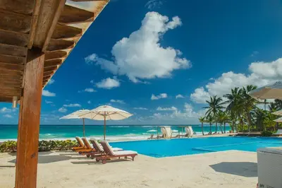 a pool at the beach with chairs and an umbrella at Apartamento de 2 Dormitorios en Hard Rock Golf in Punta Cana