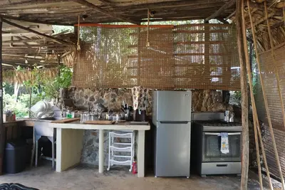 a kitchen with a table and a refrigerator and a stove at NOMAD Domes at Salto Jimenoa, Jarabacoa in Jarabacoa