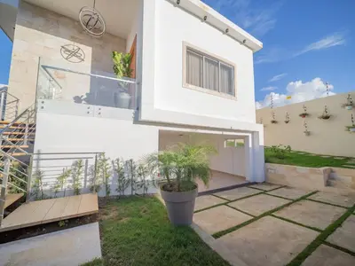 a white house with a potted plant in the yard at Luxurious Listed New Villa With 5 Br- 6 Bt In Sosua in Sosúa