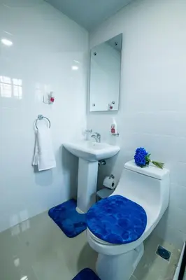 a white bathroom with a toilet and a sink at Breezes by TECASA in Santiago de los Caballeros