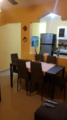 a dining room with a table and chairs and a refrigerator at Petite Lounge in Los Paredones