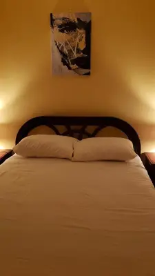 a bedroom with a white bed with a wooden headboard at Petite Lounge in Los Paredones