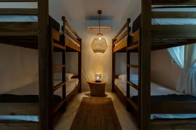 a room with three bunk beds and a lamp at Surf and Yoga Retreat for Groups Near Cab! in Gaspar Hernández