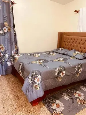 a bed with a blue comforter with flowers on it at Agradable Apartamento in Paraíso