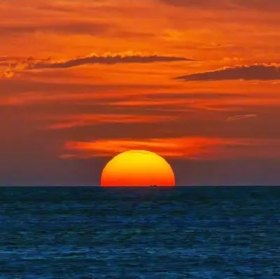 a sunset over the ocean with the sun in the horizon at Agradable Apartamento in Paraíso