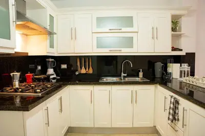 a kitchen with white cabinets and black counter tops at Riviera Azul -2 Hab con vista a la Piscina - cash only or paypal in San Felipe de Puerto Plata