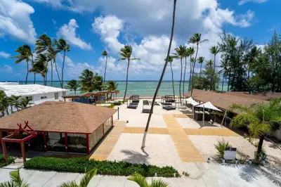 a resort on the beach with palm trees and the ocean at BeachFront Apartament - Private Beach Access in Punta Cana