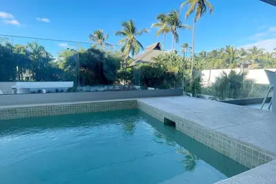 a swimming pool in front of a house with palm trees at Tropical Deluxe 2 Bedroom Unit with Picuzzi in Punta Cana