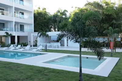 a pool with chairs and a palm tree next to a building at Tropical Deluxe 2 Bedroom Unit with Picuzzi in Punta Cana