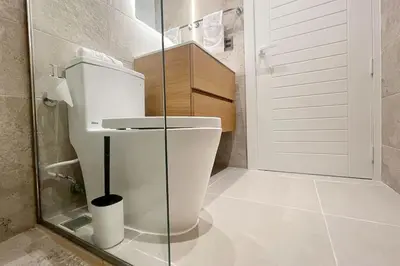 a bathroom with a toilet and a glass door at Tropical Deluxe 2 Bedroom Unit with Picuzzi in Punta Cana