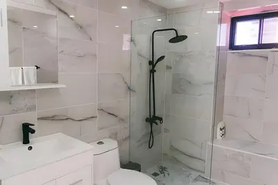 a white bathroom with a shower and a toilet at Oceanfront 3 Bedroom With Jacuzzi and Pool in Santo Domingo