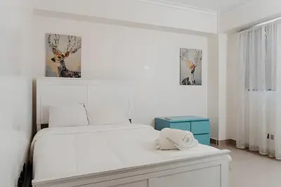a white bedroom with a bed and two pictures on the wall at Oceanfront 3 Bedroom With Jacuzzi and Pool in Santo Domingo