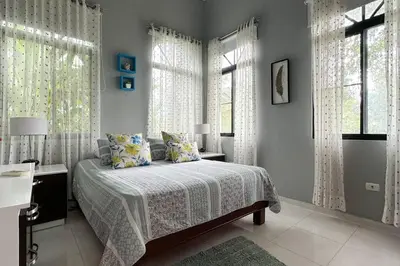 a bedroom with a bed with white curtains and windows at Private Getaway - Sosua in Sosúa